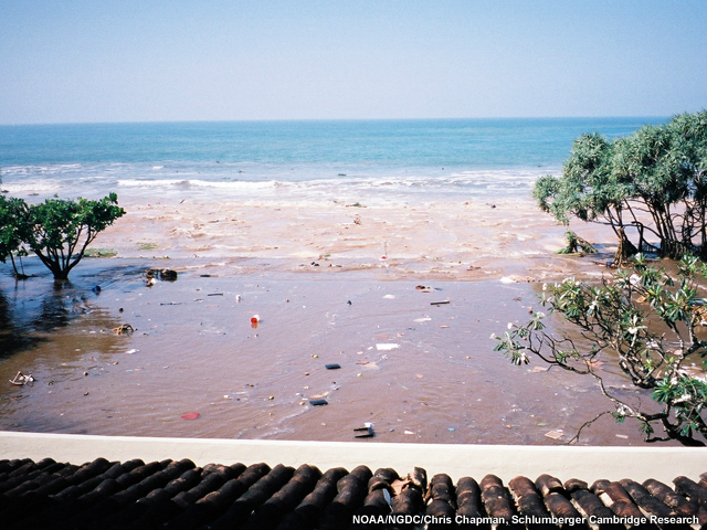 A tsunami wave receding from a beach strewn with debris in Sri Lanka during the 2004 Indian Ocean tsunami.